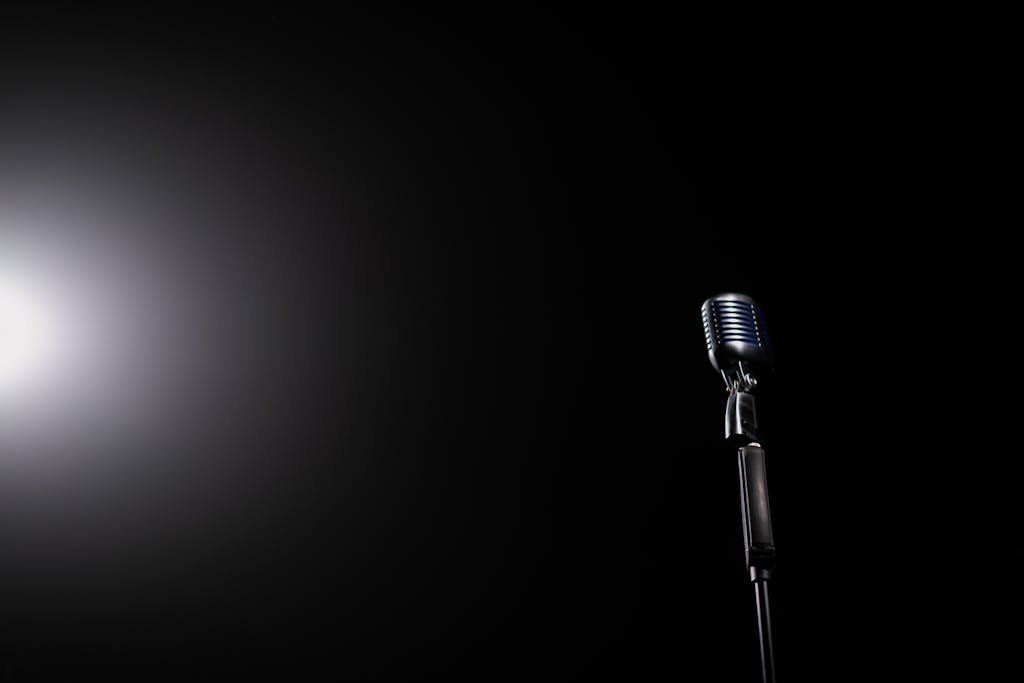 A vintage microphone illuminated by a spotlight against a dark background, perfect for music-related themes.