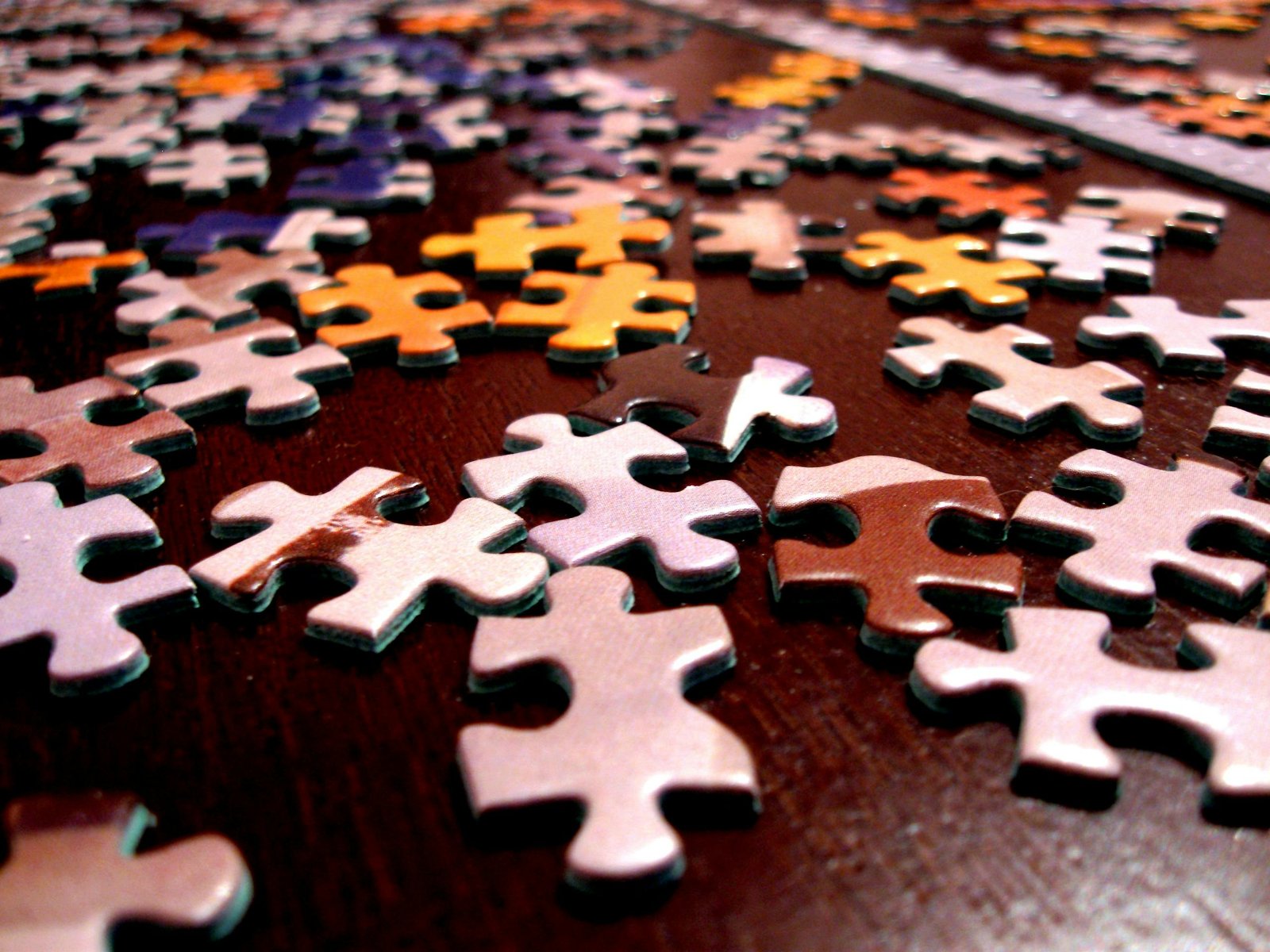 Close-up of colorful jigsaw puzzle pieces scattered on a dark surface.